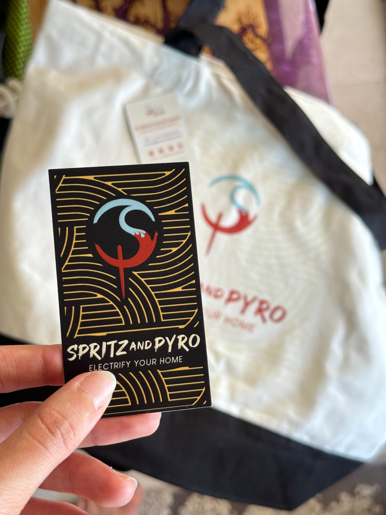 Person holding a black and gold business card with 'Spritz and Pyro' branding.